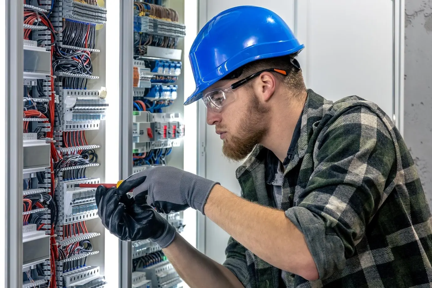 An electrician adjusts the cable connection on a switchboard tool at work.