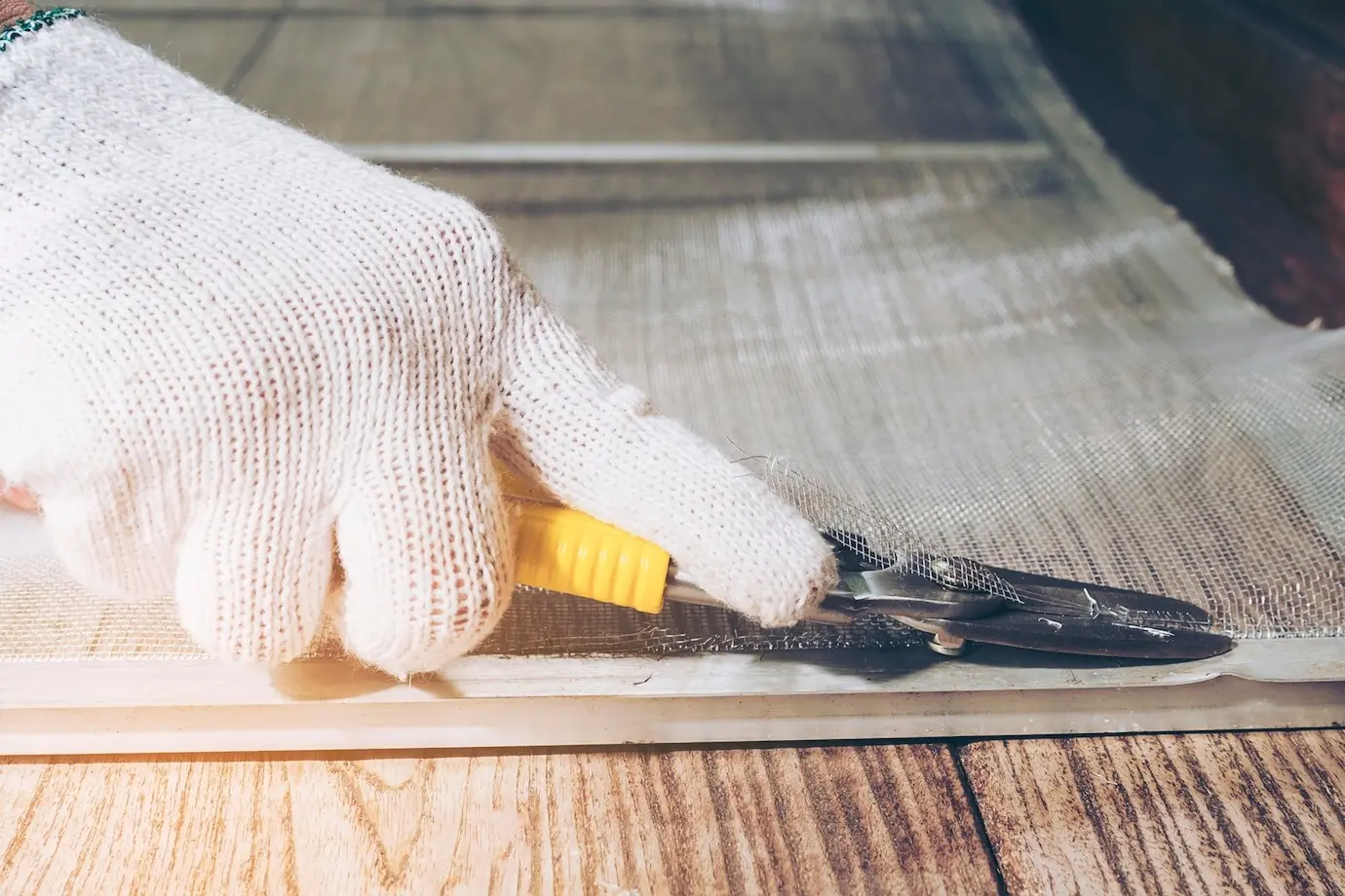 A man is working on installing a mosquito wire screen.