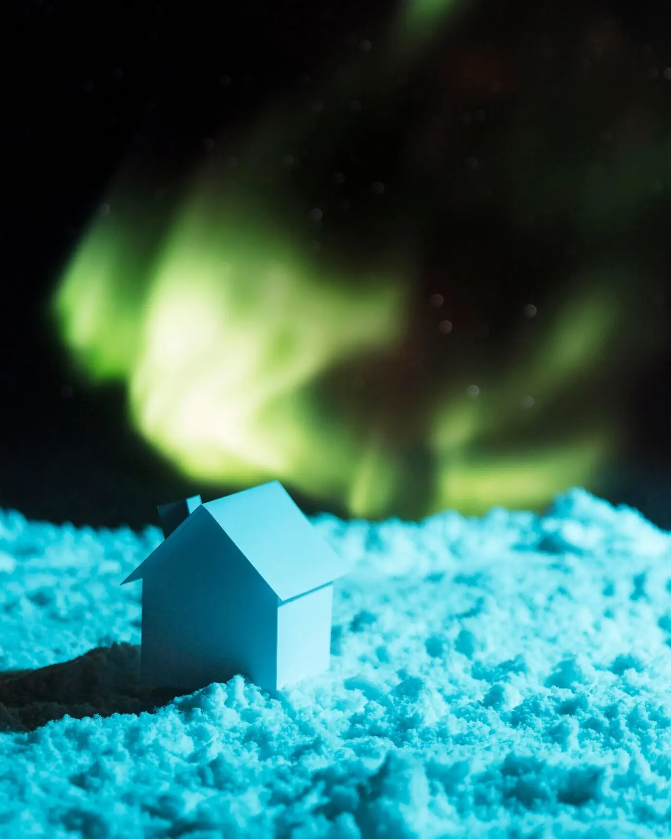 A house on the snow with the aurora borealis.